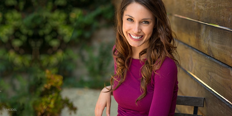 Smiling Female Sitting on Bench in Dark Pink Blouse